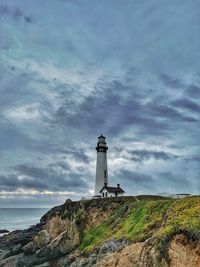 Lighthouse by sea against sky