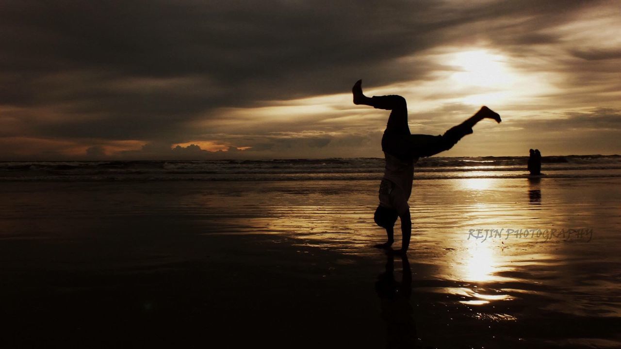 beach, sea, sunset, water, silhouette, reflection, cloud - sky, shore, full length, scenics, bird, horizon over water, playing, tranquil scene, vacations, sky, wet, tranquility, fun, sun, orange color, enjoyment, wave, mid-air, beauty in nature, nature, person, atmospheric mood