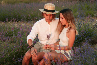 Portrait of a young cute couple in love sitting together in a field of lavender blossoms