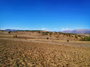 Scenic view of arid landscape against clear blue sky