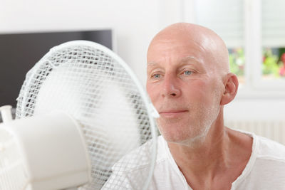 Man looking at electric fan in home