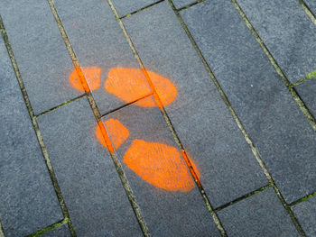 High angle view of orange shoeprint on footpath