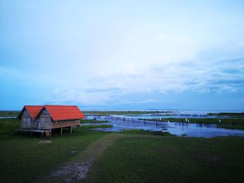 House by lake against sky