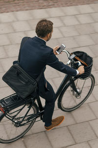 High angle view of businessman riding bicycle on footpath in city