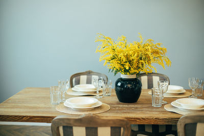 Festive easter table setting. branches of mimosa in vase. home interior.
