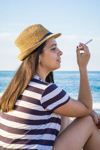 Young woman holding cigarette at beach