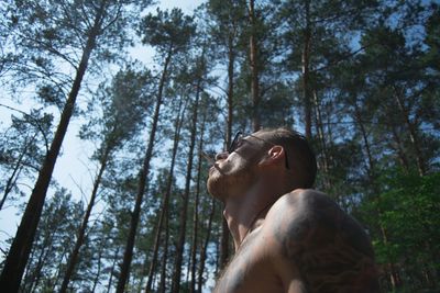 Low angle view of young man standing in forest