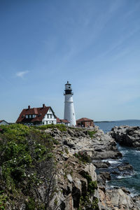 Lighthouse amidst sea and buildings against sky