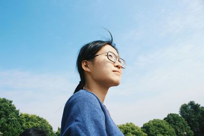 Low angle view of young woman against sky