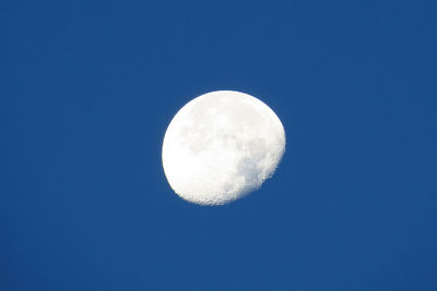 Low angle view of gibbous moon in clear blue sky