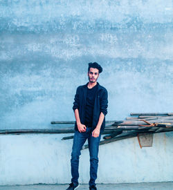 Portrait of young man standing against wall