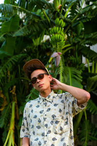 A young guy wearing summer clothing. palm tree as background.