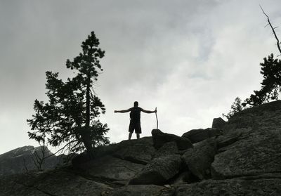 Low angle view of  man standing on cliff against sky