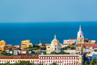 Cathedral and church in city by sea against clear sky