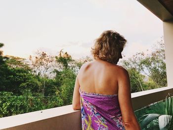 Rear view of woman standing by railing against sky