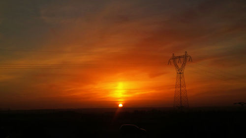 Silhouette electricity pylon against sky during sunset