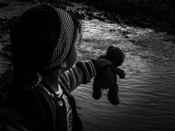 Little girl holding teddy bear over river
