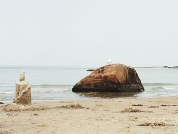 Rock on beach against clear sky