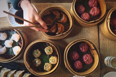 Directly above shot of hand holding food in bamboo steamer