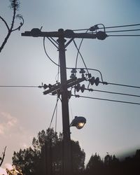 Low angle view of silhouette electricity pylon against sky