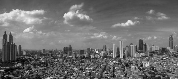 View of cityscape against cloudy sky