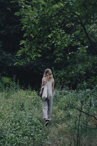 Woman standing on field in forest