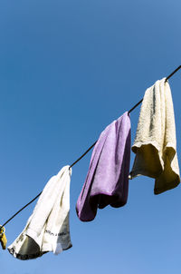 Low angle view of clothes drying against blue sky