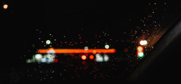 Illuminated city seen through wet glass