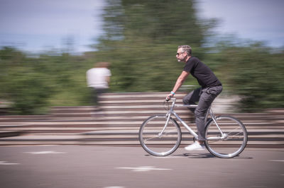 Side view of young man riding bicycle on road