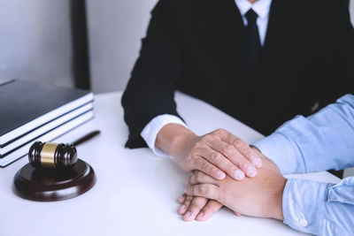 Close-up of hands holding people sitting on table