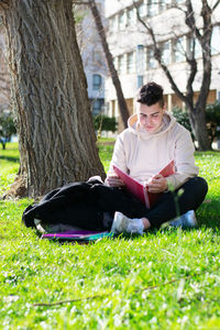 Man sitting on tree trunk in field