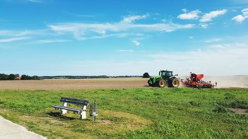 Tractor in farm against blue sky on sunny day