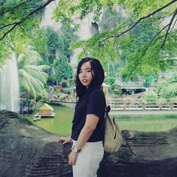 Portrait of smiling young woman standing against trees