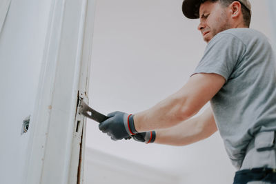 Hands of a man working with a crowbar indoors.