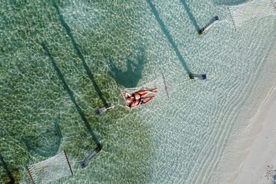 Mother and son relaxing on a hammock over the water. air view.