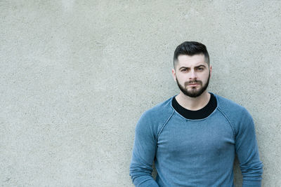 Portrait of young man standing against wall