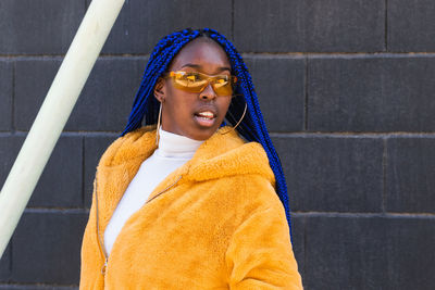 Portrait of smiling young woman standing against wall