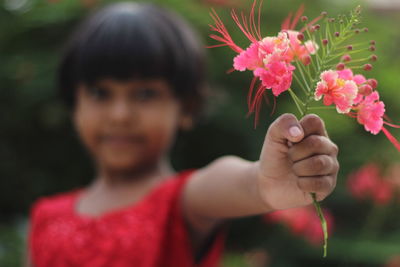 Close-up of boy holding red flowering plant