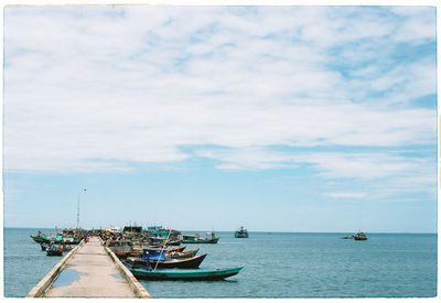 Boat sailing in sea against cloudy sky