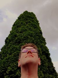 Low angle portrait of man against tree against sky