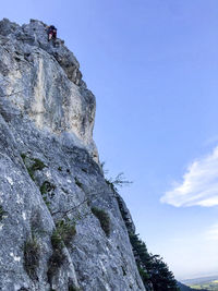 Low angle view of person on rock against sky