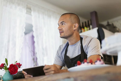 Male owner using digital tablet at cafe counter