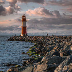 Lighthouse by sea against sky