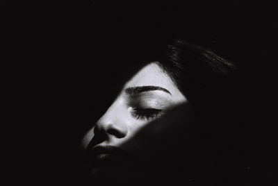 Close-up of young woman against black background