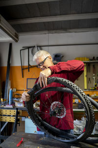 Senior man repairing bicycle tire in garage