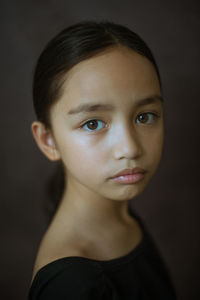 Close-up portrait of cute girl against gray background