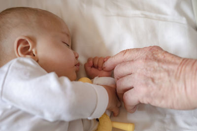 Cropped wrinkled hand touching baby at home
