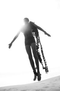 Young man in costume jumping at desert against sky