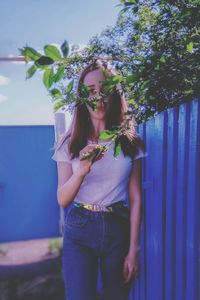 Young woman standing against plants