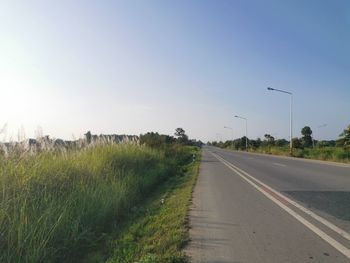 Road amidst field against clear sky